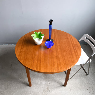 Runt matbord i teak med en iläggsskiva